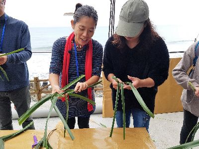 宮莉筠(左)教遊客用林投葉編織阿里鳳鳳--將另開視窗看原圖