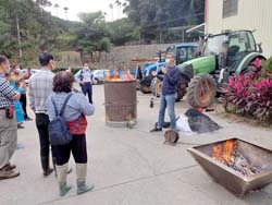 本場媒合不同種類的農場，期望農場主善加利用彼此的資源。倪禮豐助研員（右一）並示範稻殼（圓筒）及樹木枝幹（方型）簡易生物炭方法，讓農友可於田區將自家農產副產物自製成生物炭使用